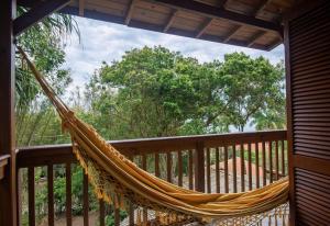 a hammock on a deck with trees in the background at Pousada Casa do Ceo in Praia do Rosa