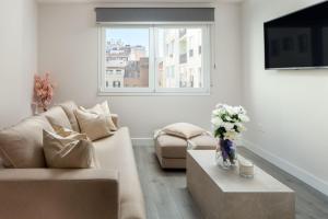 uma sala de estar com um sofá e uma mesa com flores em INMálaga Plaza De Las Flores em Málaga