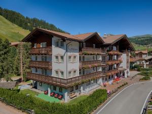 a large building with balconies and a road at Hotel Genziana in Selva di Val Gardena