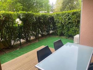 a table and chairs on a deck with a hedge at Superbe appartement dans résidence avec piscine in Toulouse