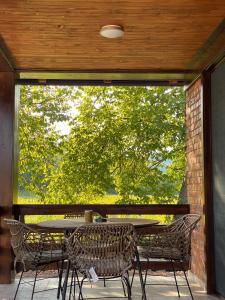 un tavolo e sedie su un patio con una grande finestra di Tri vrbe a Ljubovija