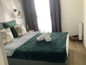 a bed with a green comforter with a roll on it at Immodēly & la Magie de Disney in Serris