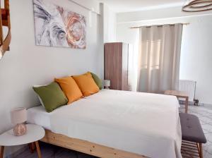1 dormitorio con 1 cama blanca con almohadas de color naranja y verde en Zoi's Hοuse.Vacation home in Mani near Vathi beach, en Vathí