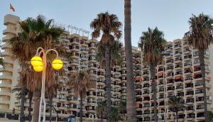 duży budynek apartamentowy z palmami i światłem ulicznym w obiekcie Aloha Beach Vibe w mieście Benalmádena