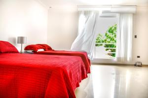 Cama roja en habitación blanca con ventana en Hotel Senses Equipetrol, en Santa Cruz de la Sierra