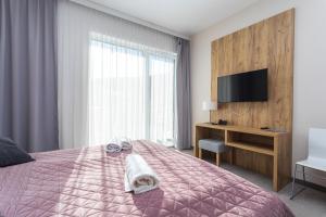 Aparthotel Apartamenty Czarna Góra 308 في سيينا: غرفة نوم مع سرير وتلفزيون ومكتب