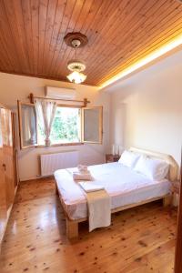 sypialnia z dużym łóżkiem i drewnianym sufitem w obiekcie Villa Artemis Leto w mieście Artemida