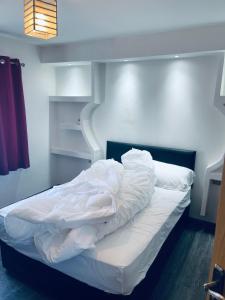 een bed met witte lakens en kussens in een kamer bij UNIQUE ROOMS! 4beds double bed in Farnworth