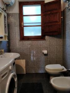 a bathroom with a toilet and a sink and a window at Casa Margherita in Càbras