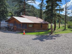 una cabaña de madera con un cono naranja delante de ella en Chinook Cabins & RV Park, en South Fork