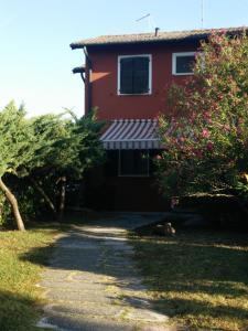 una casa roja con toldo blanco y árboles en Fiordo Appartamento 1331 Isola di Albarella, en Isola Albarella