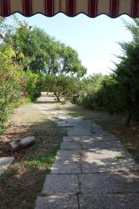 un camino de piedra con árboles y arbustos en un parque en Fiordo Appartamento 1331 Isola di Albarella, en Isola Albarella