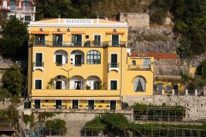 un edificio giallo sul fianco di una montagna di Palazzo Margherita a Positano