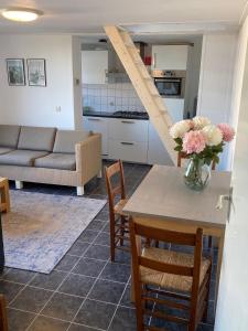 een woonkamer met een tafel met een vaas met bloemen erop bij Schrijvershuisje - sfeer & stilte Zeeuws Vlaanderen in Zaamslag