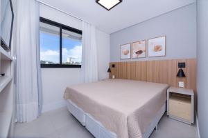 a white bedroom with a bed and a window at Adra 205 - Apartamento no centro de Bombinhas - Rooftop com piscina e academia - À poucos metros da praia - (Consultar serviços de roupas de cama e banho) in Bombinhas +39 photos