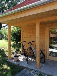 dos bicicletas están estacionadas bajo un cobertizo de madera en CSENDÜLŐ VENDÉGHÁZ en Noszvaj
