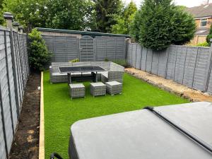 un patio trasero con una mesa, bancos y una valla en Redfearn Cottage en Apperley Bridge