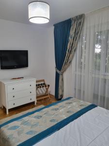a bedroom with a bed and a tv and a dresser at Apartament QUIET in Galaţi