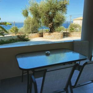 einen blauen Tisch und Stühle auf einem Balkon mit einem Baum in der Unterkunft SUNSET Luxury Accommodation in Verga Kalamata