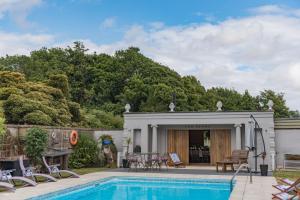 a swimming pool with chairs and a house at Bacchus by Bloom Stays in Canterbury