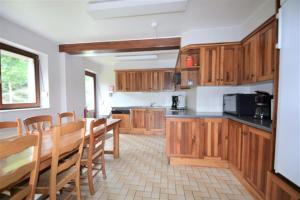 a kitchen with wooden cabinets and a table and chairs at Achouffe - MASSON in Houffalize