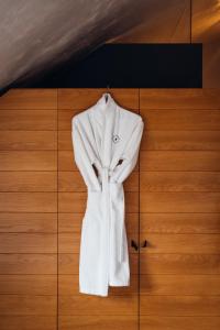 a white robe hanging on a wooden wall at HOT_elarnia Hotel & Spa in Puszczykowo