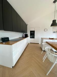 a kitchen with white cabinets and a table with chairs at Magnifique villa avec piscine, à 5 min des plages in Landunvez