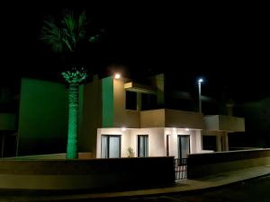 a building with a palm tree in front of it at night at PylaApts - Apartments near the beach in Pyla