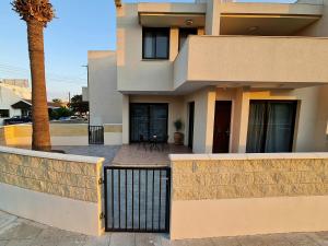 a house with a fence and a palm tree at PylaApts - Apartments near the beach in Pyla