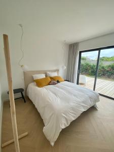 a bedroom with a white bed with a large window at Magnifique villa avec piscine, à 5 min des plages in Landunvez