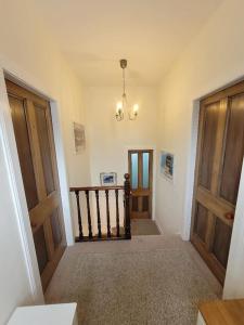 a hallway with two wooden doors and a chandelier at Character cottage in centre of Moffat in Moffat