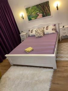a bedroom with a bed with purple sheets and pillows at Apartament Gabriela 39 in Baia Mare