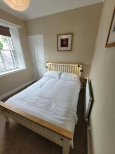 ein weißes Bett in einem Zimmer mit Fenster in der Unterkunft Character cottage in centre of Moffat in Moffat