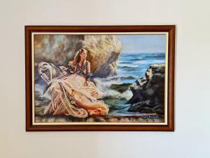 a framed painting of a woman on the beach at PylaApts - Apartments near the beach in Pyla +37 photos