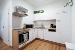 eine Küche mit weißen Schränken und einem Herd in der Unterkunft CozyNite Premium Apartment Schönbrunn 1 in Wien
