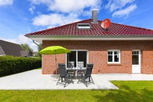 d'une terrasse avec une table, des chaises et un parasol vert. dans l'établissement Ferienhaus Nordseeperle Neuharlingersiel, à Neuharlingersiel