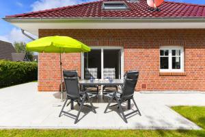 a table with four chairs and a yellow umbrella at Ferienhaus Nordseeperle Neuharlingersiel in Neuharlingersiel
