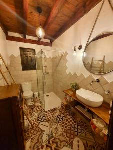 a bathroom with a sink and a toilet and a mirror at Finca La Portilla in Aroche