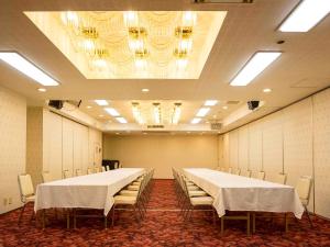 uma sala de conferências com mesas e cadeiras e um lustre em City Hotel Air Port in Prince - Vacation STAY 80750v em Izumi-Sano
