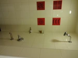 baño con 2 grifos y suelo de baldosa blanca en Red Fox Hotel, Hitech city, Hyderabad en Hyderabad