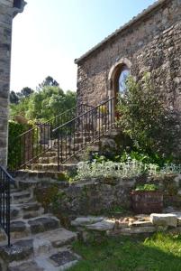 un antiguo edificio de piedra con escaleras y una valla en Gite rural au calme en Cévennes Gardoises, en Saint-Jean-du-Gard