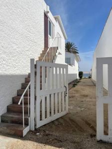 ein weißes Tor neben einem weißen Haus mit Treppen in der Unterkunft Departamento pequeño 2 BR en zona ideal de Paracas in Paracas
