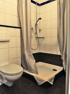La salle de bains est pourvue d'une douche, de toilettes et d'un rideau de douche. dans l'établissement Ferien-Messe-Handwerker- Apartment Bensberg, à Bergisch Gladbach