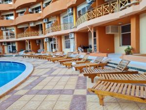 a hotel with a pool and wooden benches at Oasis resort-Nice Condo -B31-Al Ahyaa - Hurghada in Hurghada