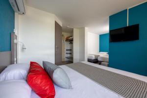 a bedroom with a bed with red and white pillows at The Originals City, Hôtel Mâcon Sud in Chaintré