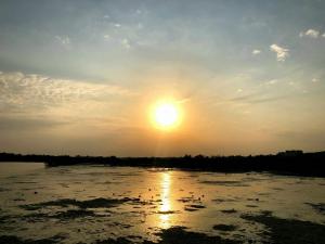 a sun setting over a body of water at PylaApts - Apartments near the beach in Pyla
