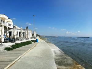 a sidewalk next to the ocean with umbrellas at PylaApts - Apartments near the beach in Pyla