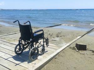 a black wheelchair sitting on a dock on the beach at PylaApts - Apartments near the beach in Pyla