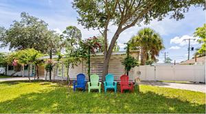 quatre chaises colorées assises dans l'herbe dans une cour dans l'établissement Close to beaches with hot tub and large garden, à Sarasota