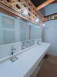 a white bathroom with a sink and a mirror at El Gordo's Seaside Adventure Lodge in El Nido